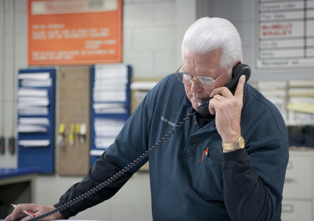 An auto repairman answers phone calls